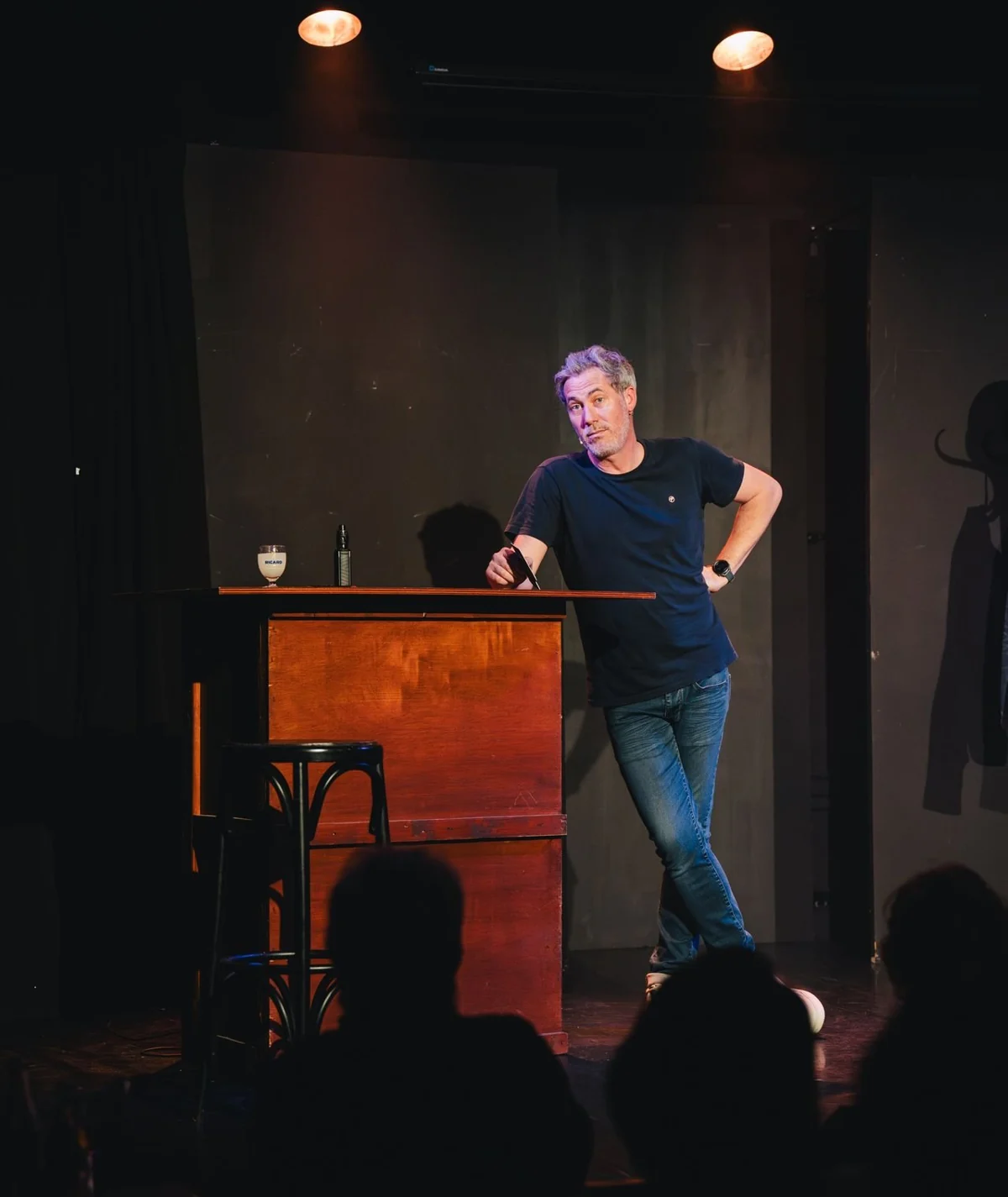Daniel Camus accoudé au comptoir de son bar face au public, dans son spectacle Happy Hour