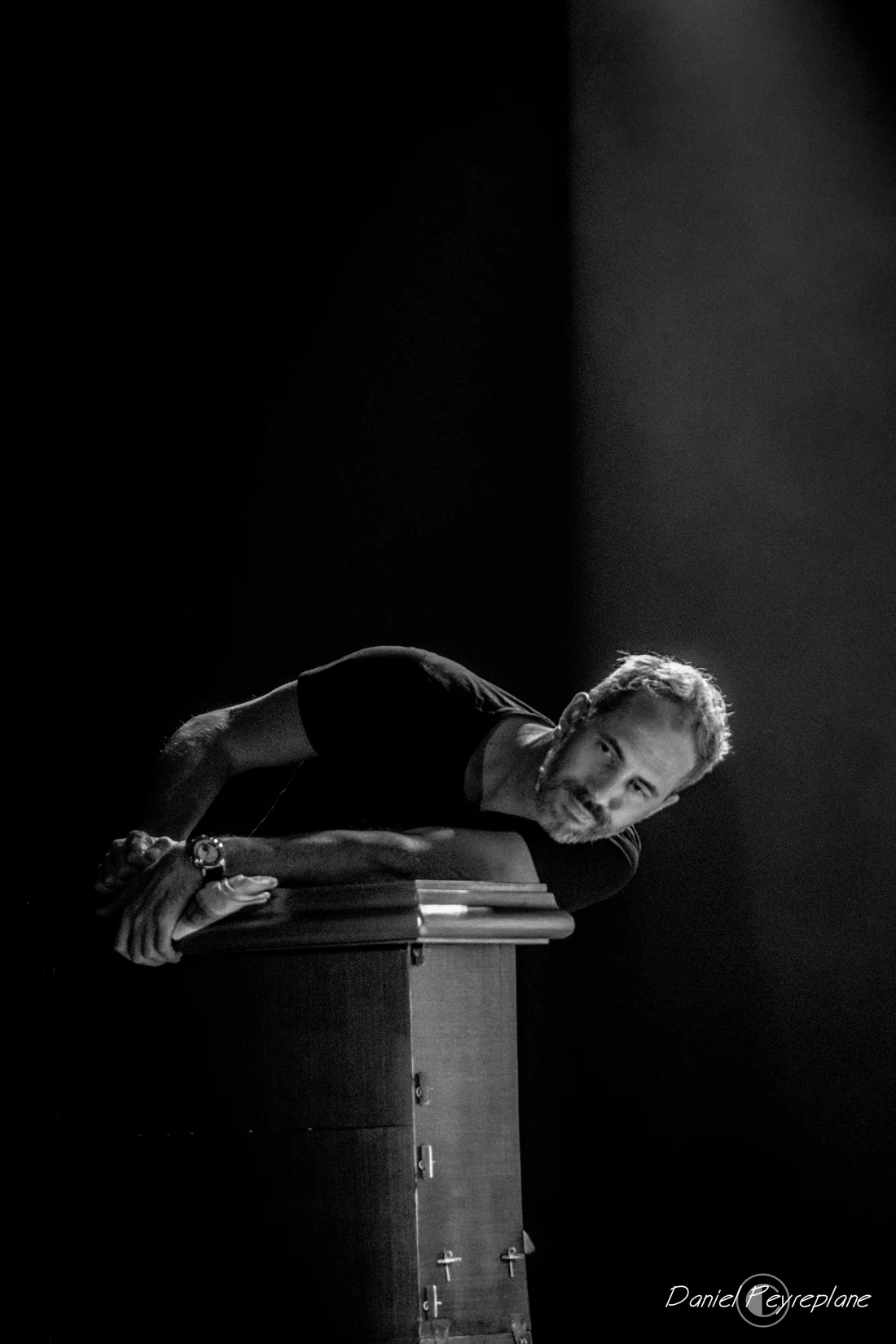 Daniel Camus penché sur une colonne dans la pénombre, scène du spectacle Happy Hour